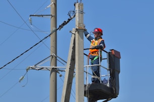 a man standing on top of a metal pole next to power lines