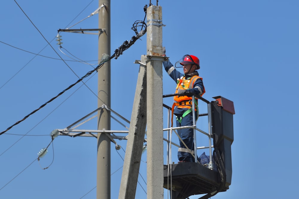 a man standing on top of a metal pole next to power lines