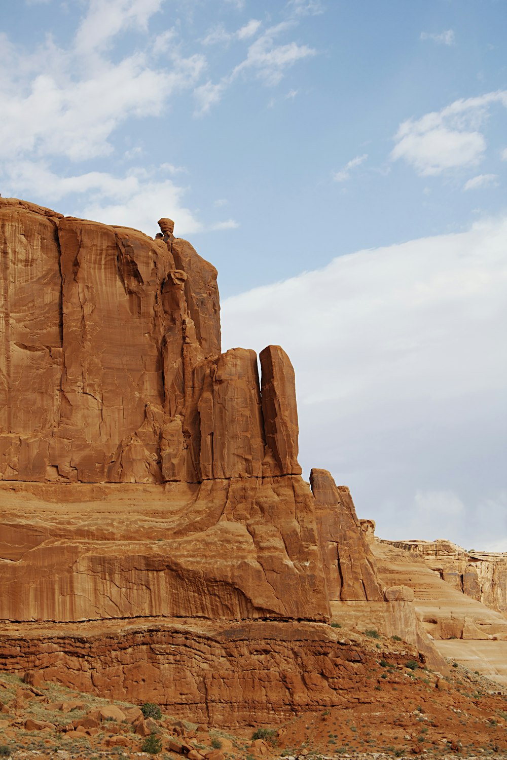 person in yellow shirt sitting on brown rock formation during daytime