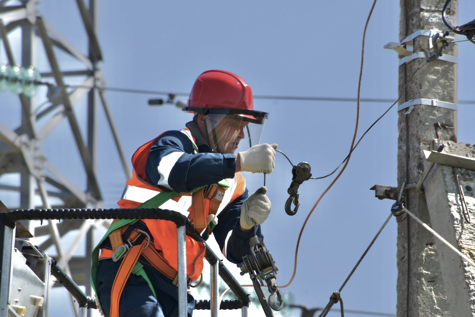 Técnico con equipo de seguridad trabajando en un poste de energía