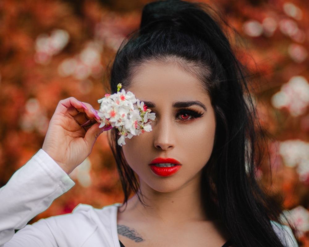 woman in white long sleeve shirt holding white flower