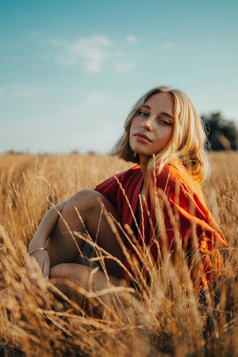 woman in red and black plaid scarf sitting on brown grass field during daytime