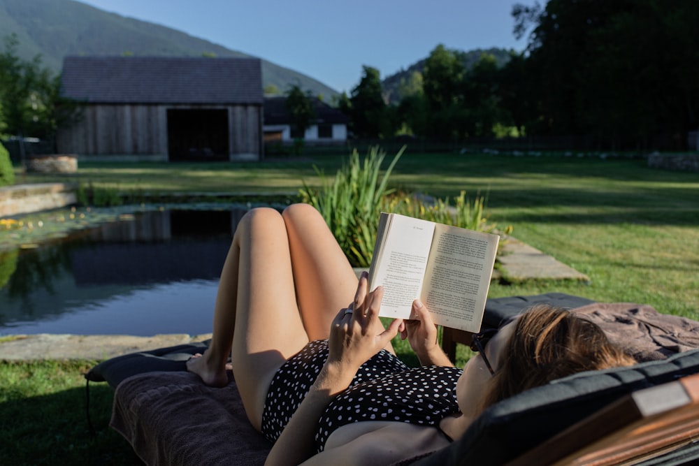 woman in black and white polka dot dress reading book