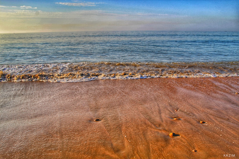 brown sand near body of water during daytime