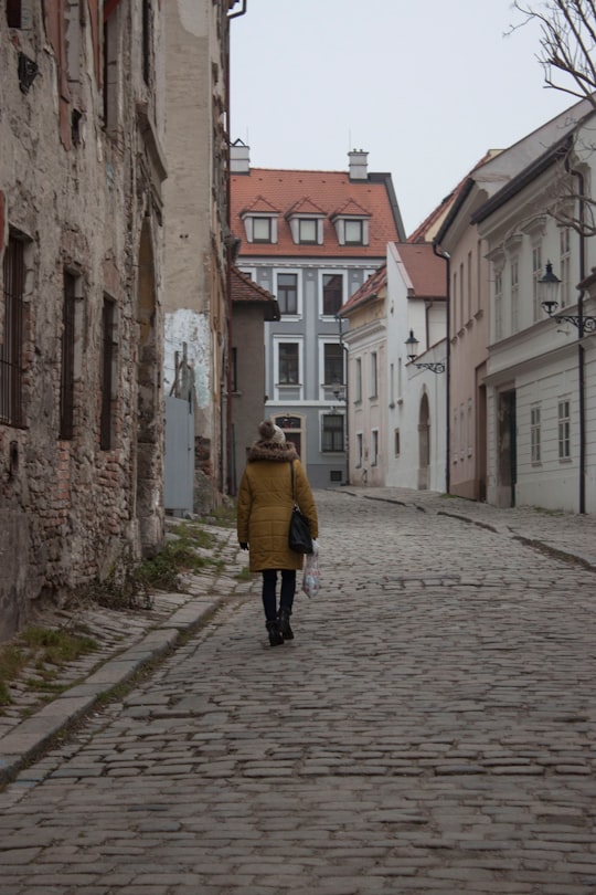 woman in yellow coat walking on street during daytime in Bratislava Slovakia