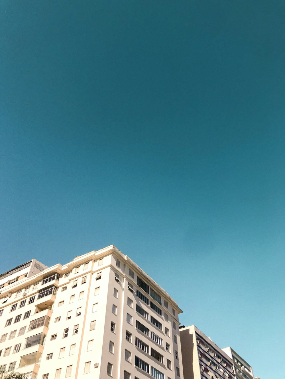 Weißes Betongebäude unter blauem Himmel tagsüber