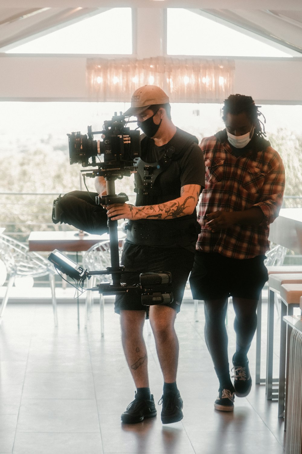 man in orange and white plaid dress shirt and black shorts standing beside man in black