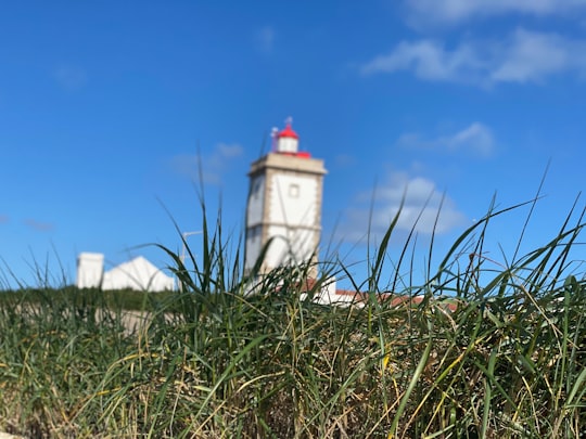 white and red lighthouse under blue sky during daytime in Peniche Portugal