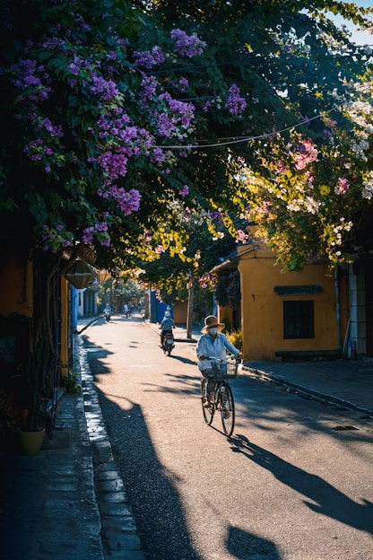 a man riding a bike down a street next to trees