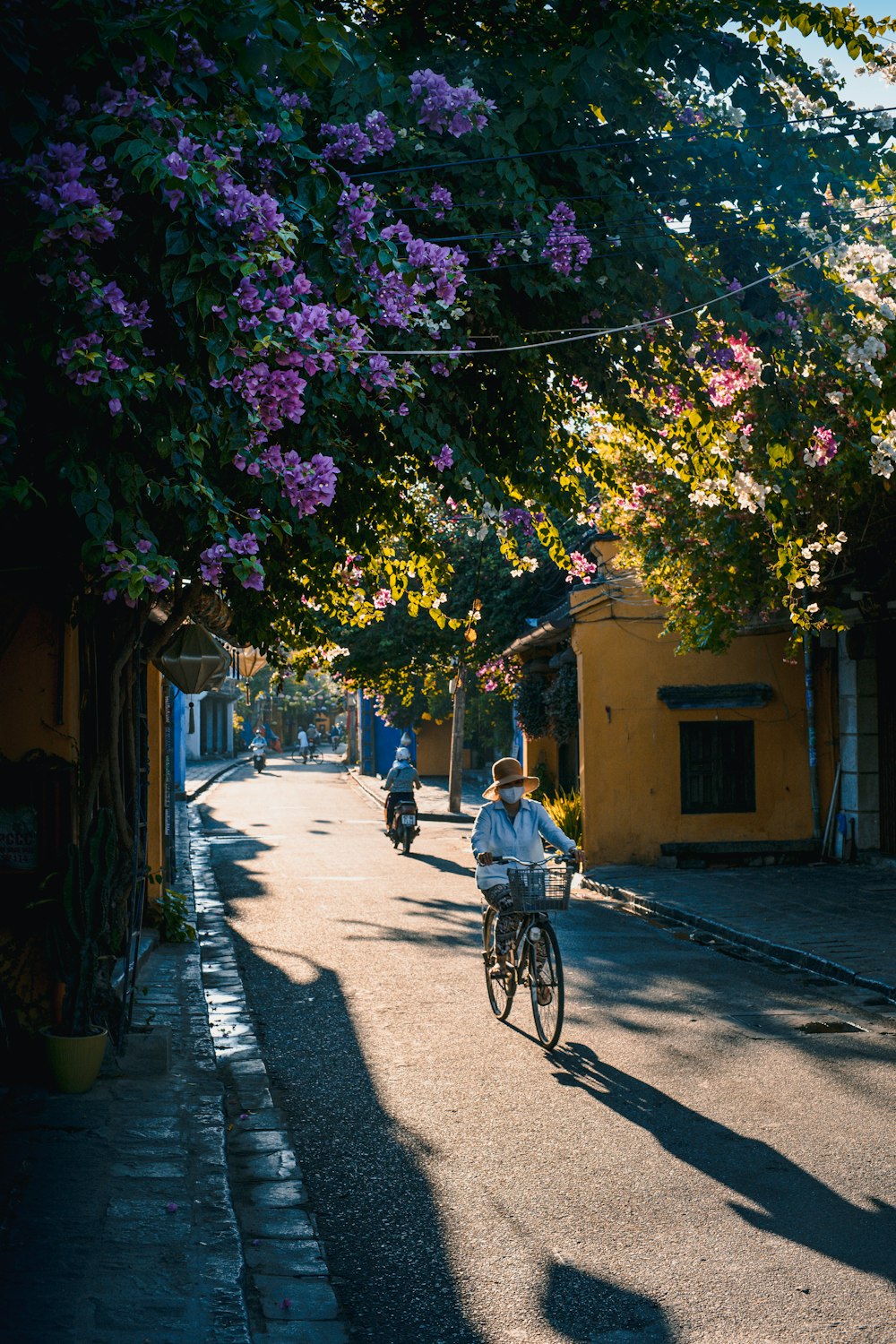 a man riding a bike down a street next to trees