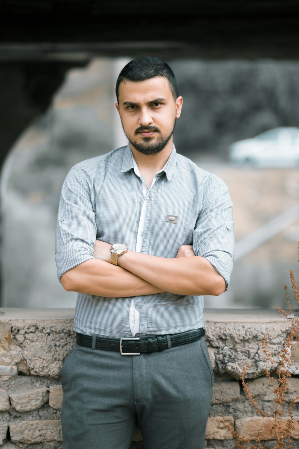 man in blue dress shirt and black denim jeans standing near brown rock during daytime