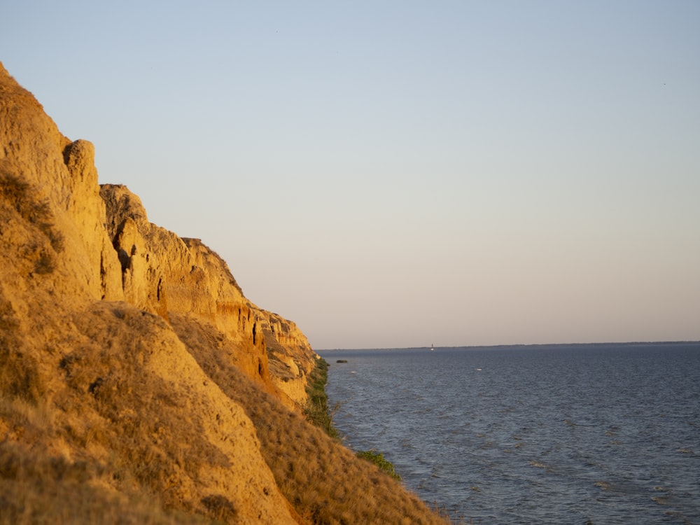 brown rocky mountain beside blue sea under white sky during daytime