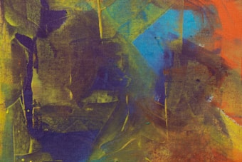 A vibrant abstract painting featuring an interplay of various colors and shapes. Bold strokes of yellow, green, purple, blue, and orange blend into one another, creating dynamic patterns and textures. The canvas shows an expressive use of color and form, suggestive of movement and energy.