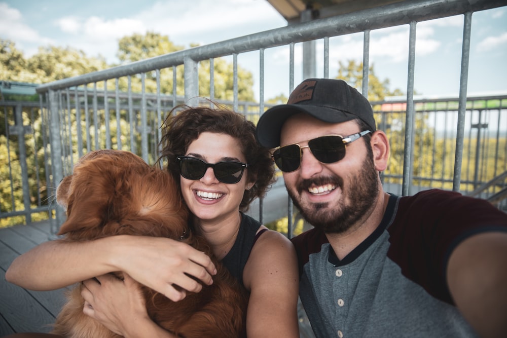 man in black sunglasses hugging brown long coated dog