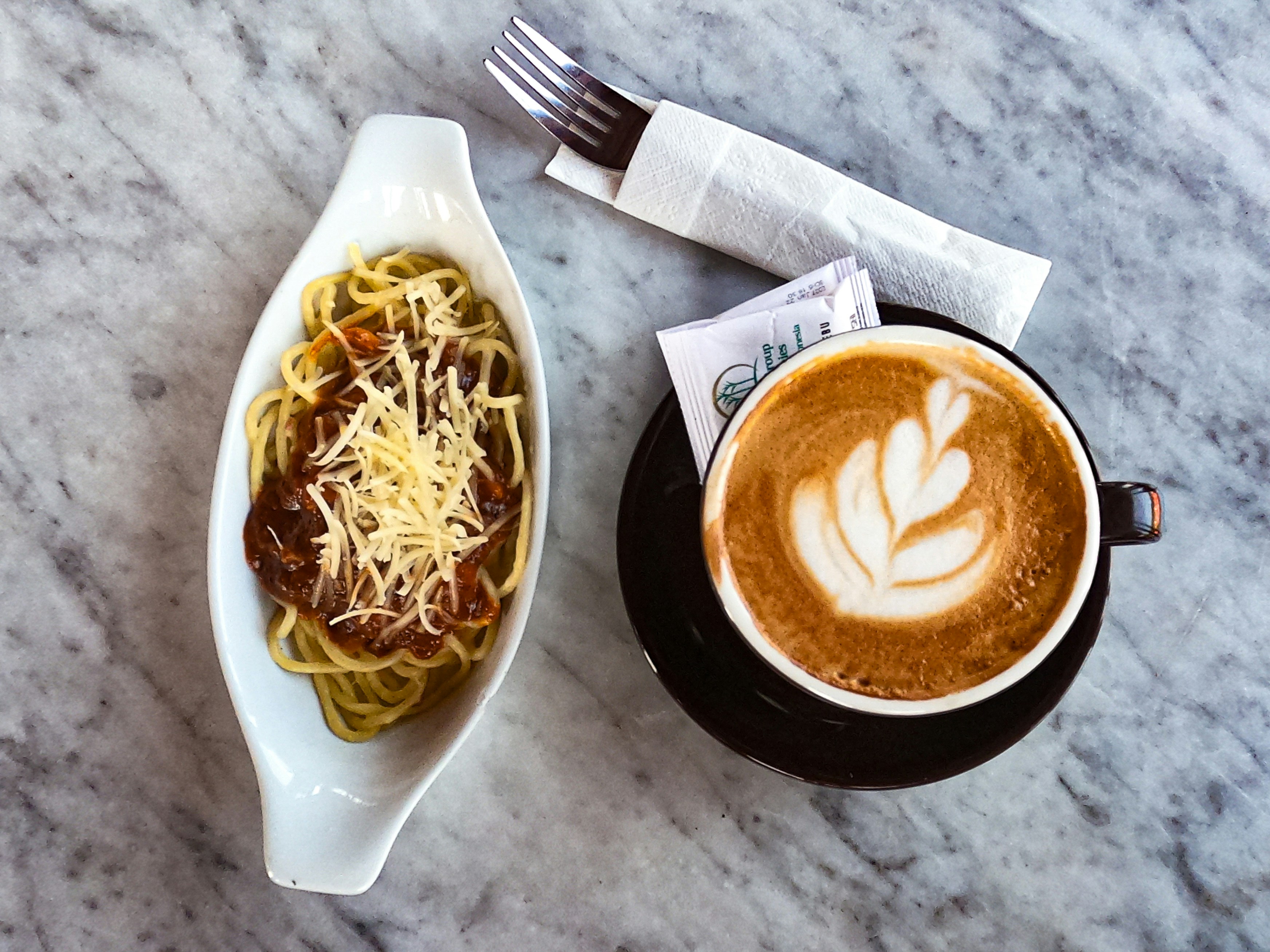 Spaghetti beside a latte with latte art