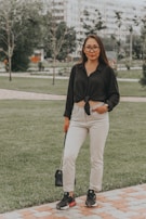 A woman holding a trendy handbag while walking in a park.