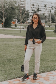 A woman holding a trendy handbag while walking in a park.