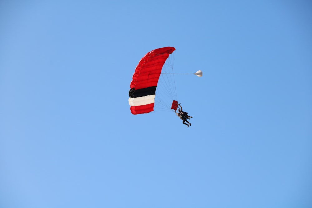 person in red parachute under blue sky during daytime