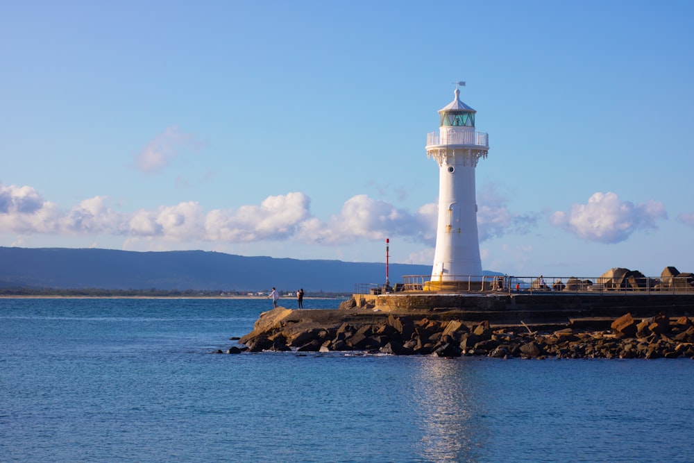 white lighthouse on brown rock formation near body of water during daytime