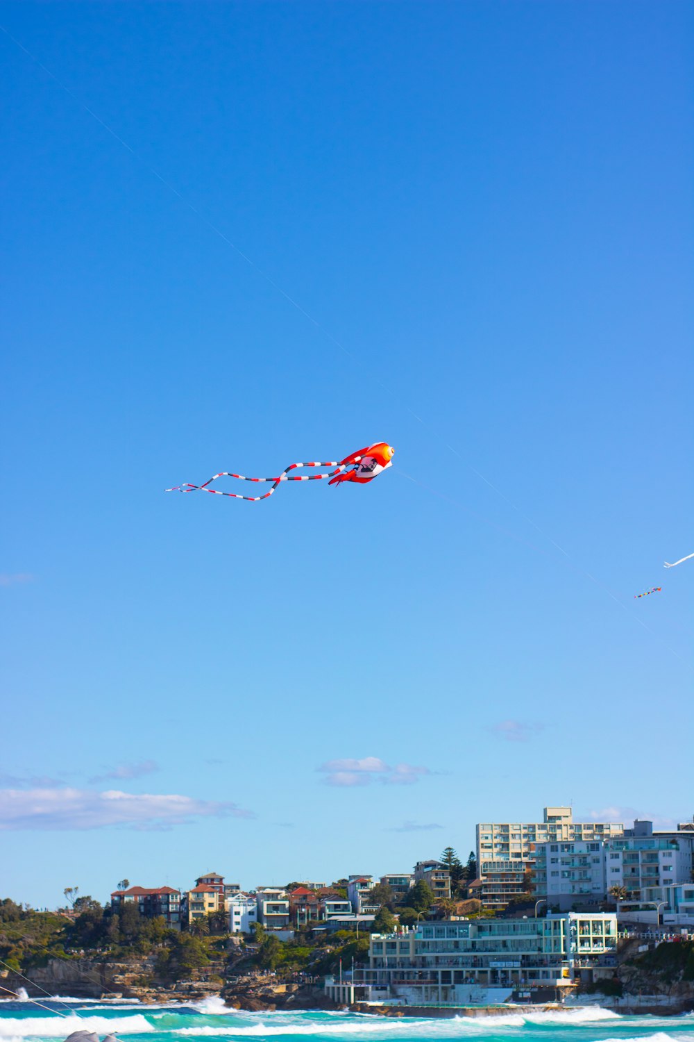 orange and yellow kite flying over city buildings during daytime