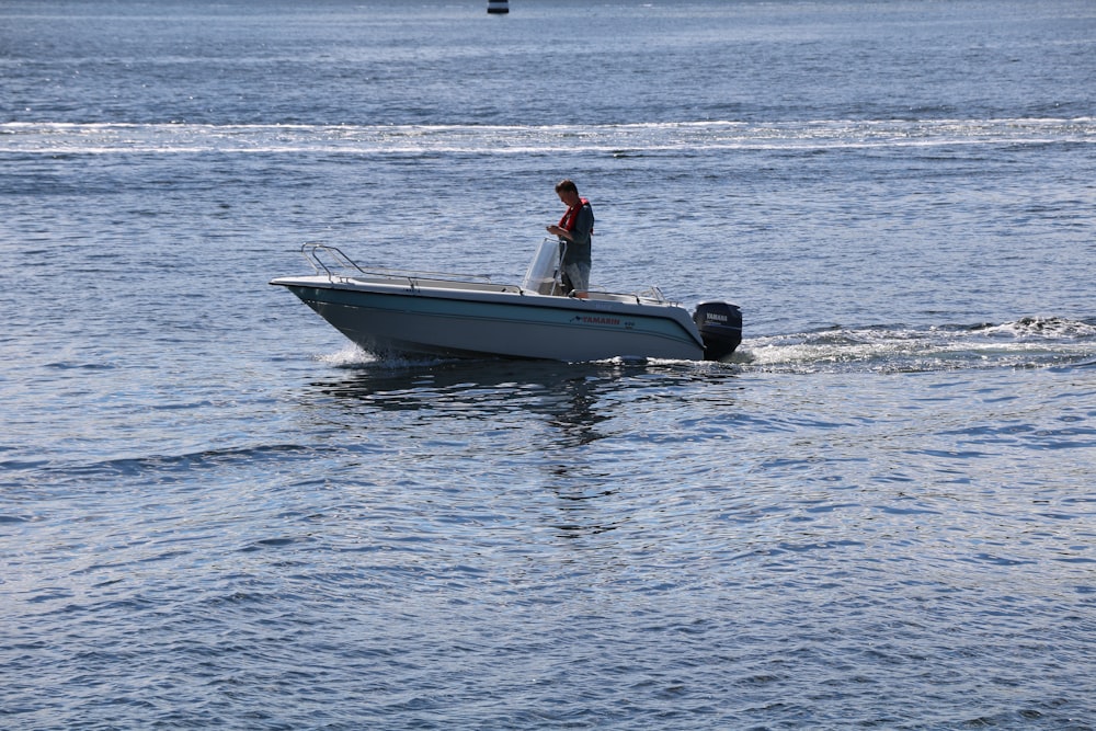 man in red shirt riding on white and black boat on sea during daytime