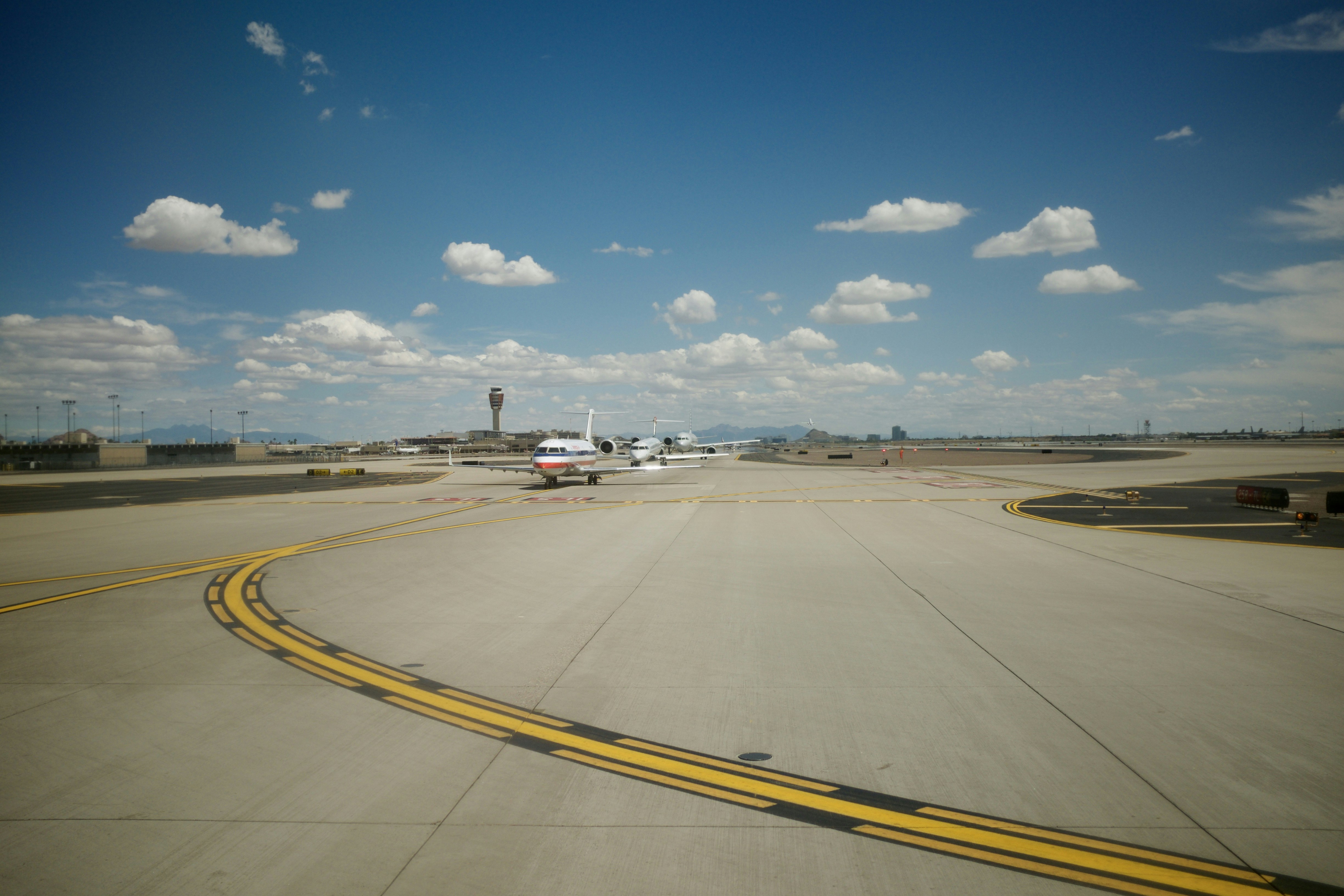 white and black plane on gray concrete road under blue sky during daytime, Airplanes in line to take off at Phoenix Sky Harbor.