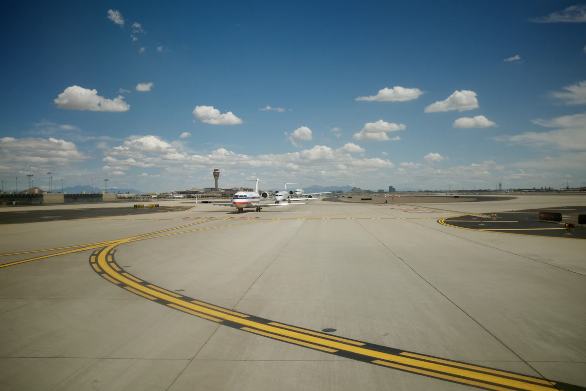 A white and black passenger plane on an airport runway under a blue sky