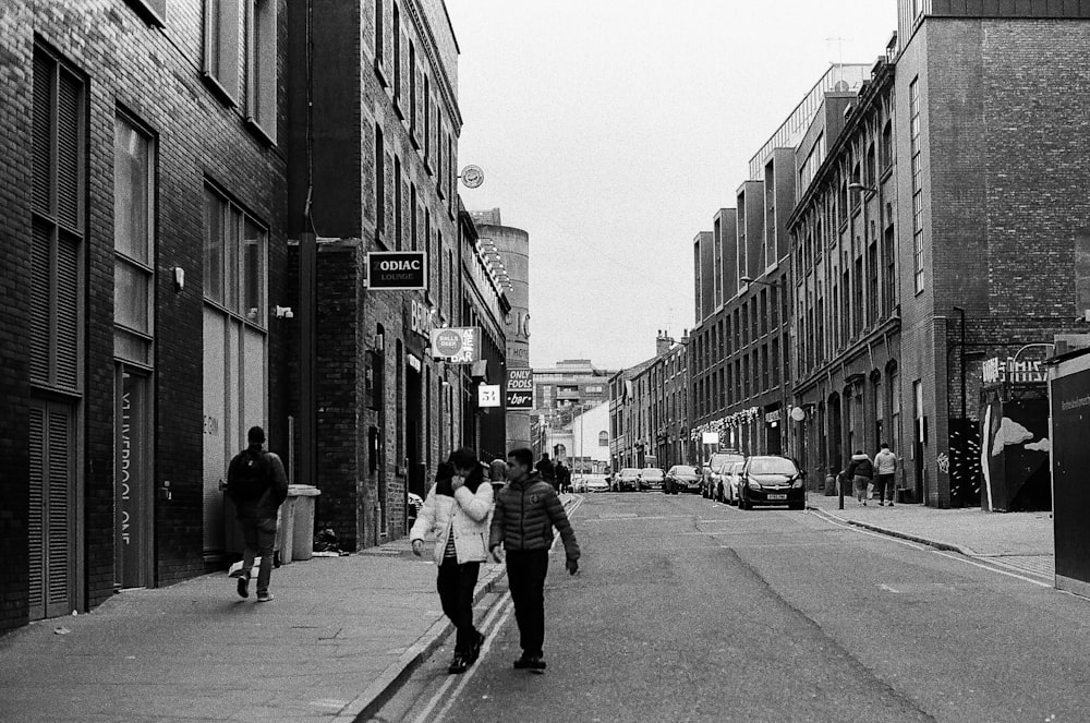 grayscale photo of people walking on sidewalk