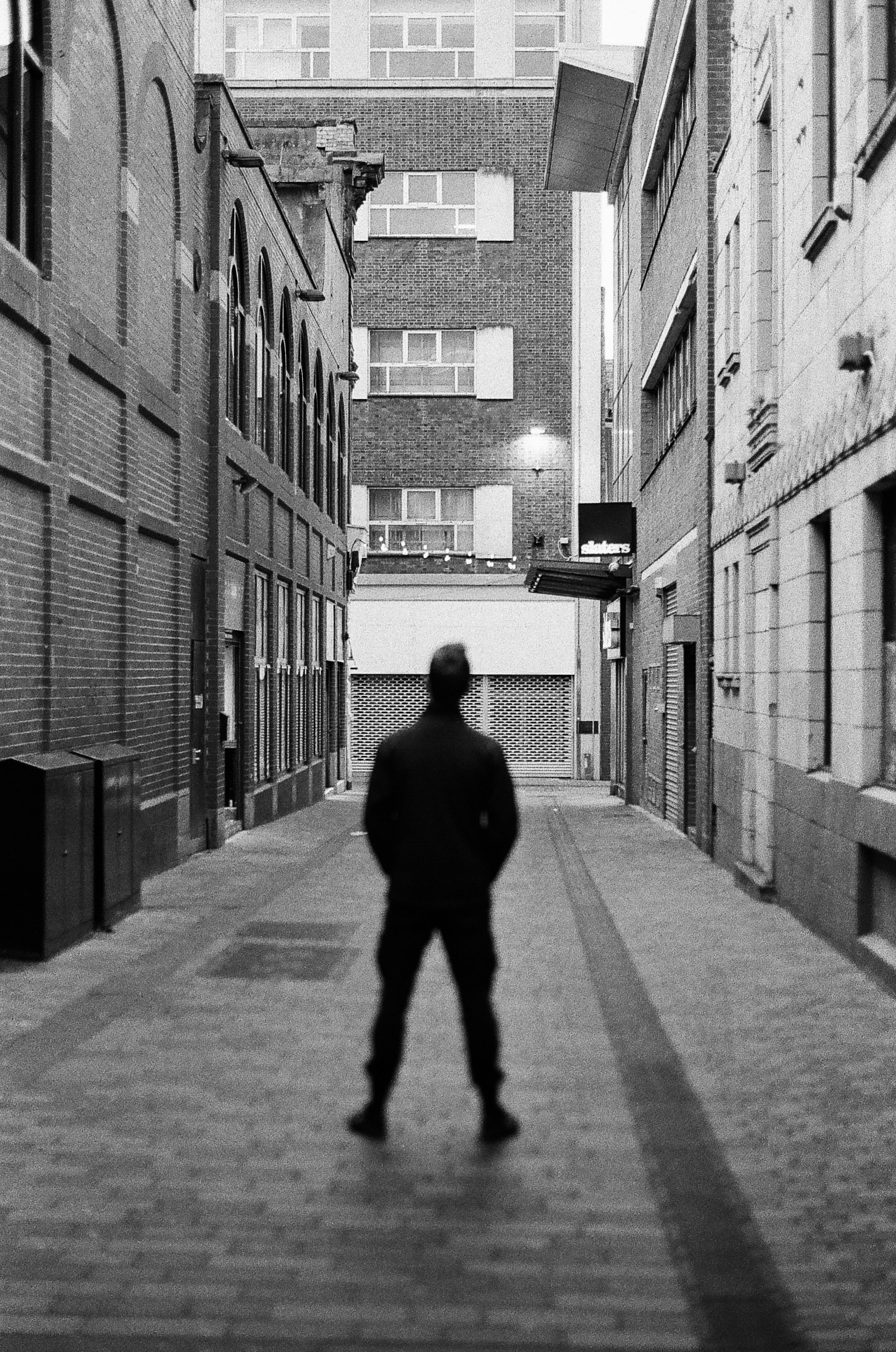 A dramatic black and white photograph showcasing a shadowy figure in a dimly lit alley, embodying the essence of film noir.