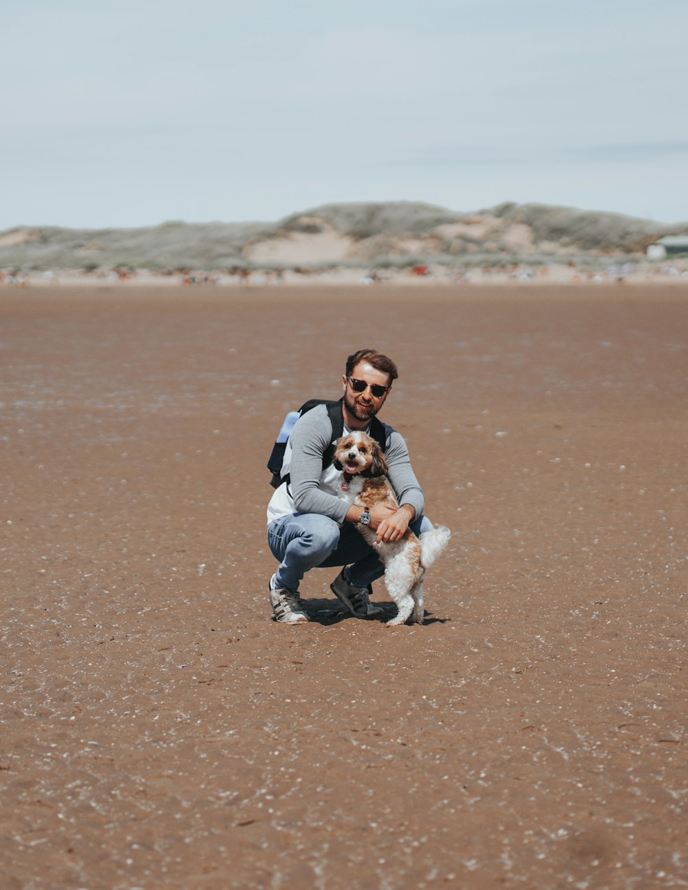 a man kneeling down with a dog on a beach