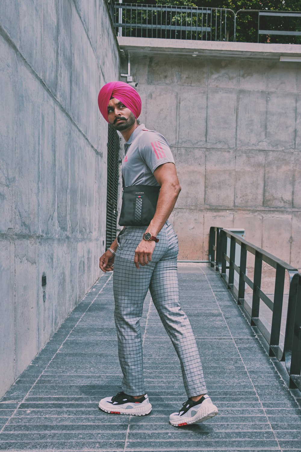 man in gray t-shirt and gray pants standing on gray concrete bridge during daytime