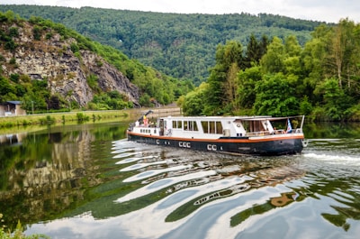 A sleek autonomous vessel smoothly navigating a calm river surrounded by lush greenery.
