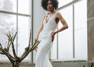 woman in white wedding dress standing beside green plant