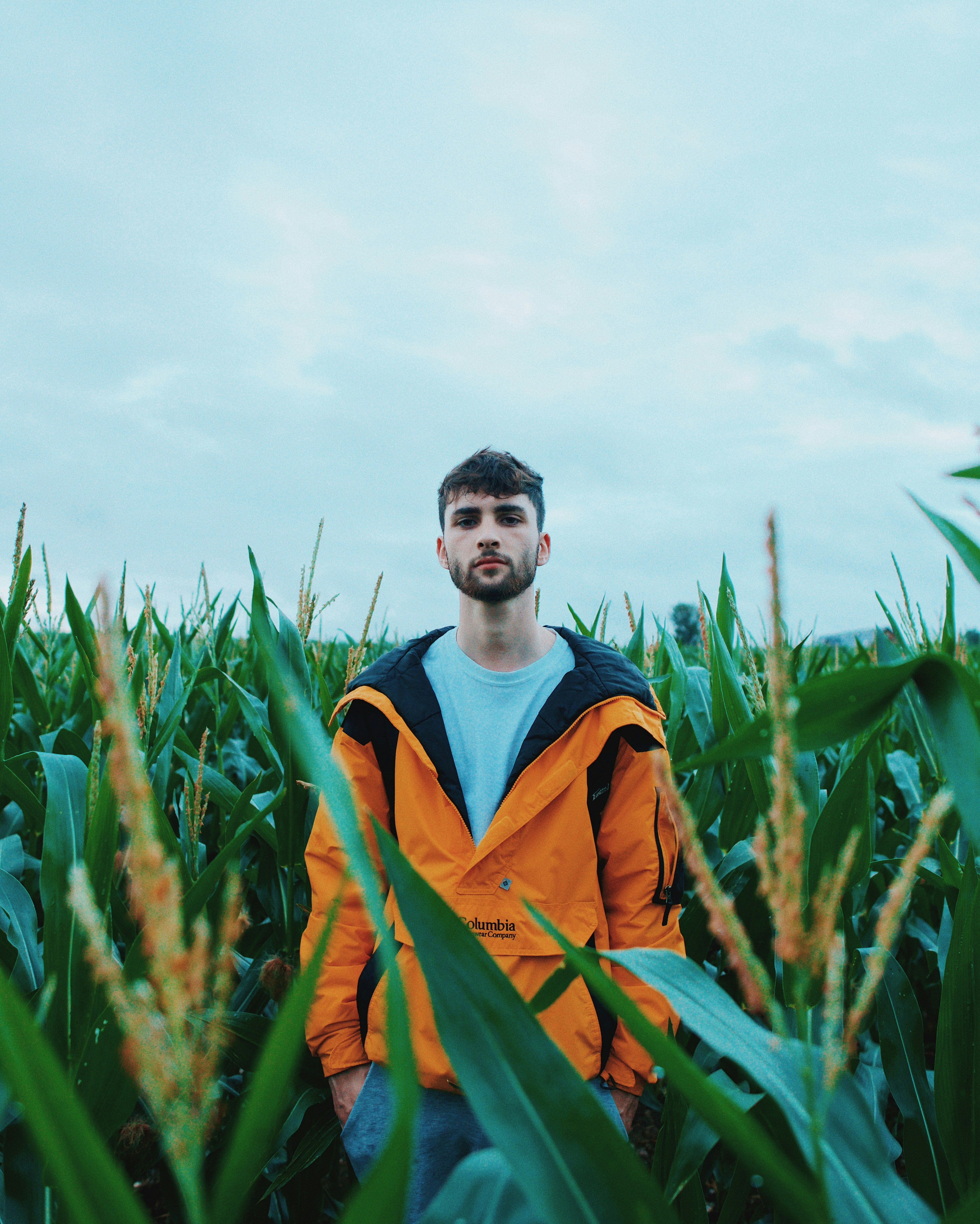 man in orange jacket standing on green grass field during daytime