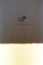 A primarily beige and dark brown image with a symbol in the center indicating image upload, featuring a small icon of a picture with a plus sign surrounded by text reading 'Drop your images here or Browse'. The bottom portion has a light leak effect.