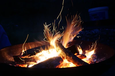 A close-up of a campfire crackling with glowing embers under a starry night sky