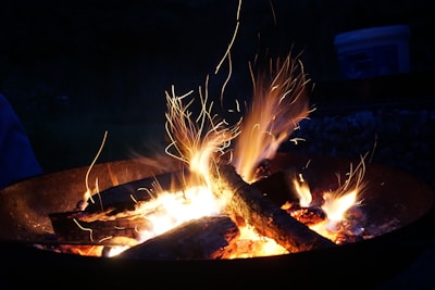 Close-up of a campfire flickering under a starry night sky in the woods.
