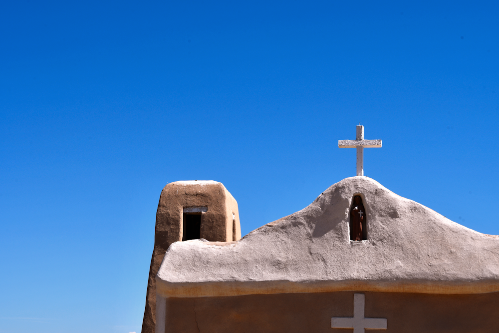 white cross on top of gray concrete building under blue sky during daytime