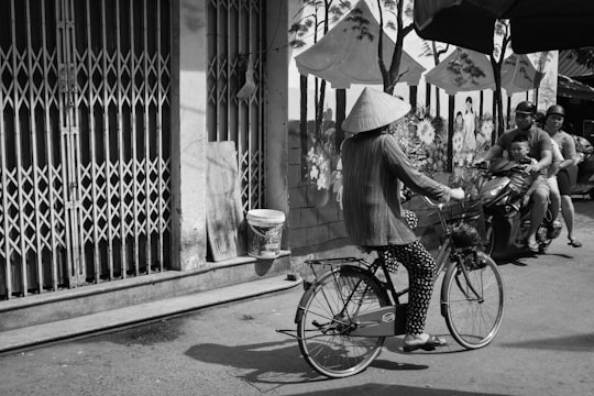 woman in white dress holding umbrella walking on sidewalk in grayscale photography in Hai Phong Vietnam