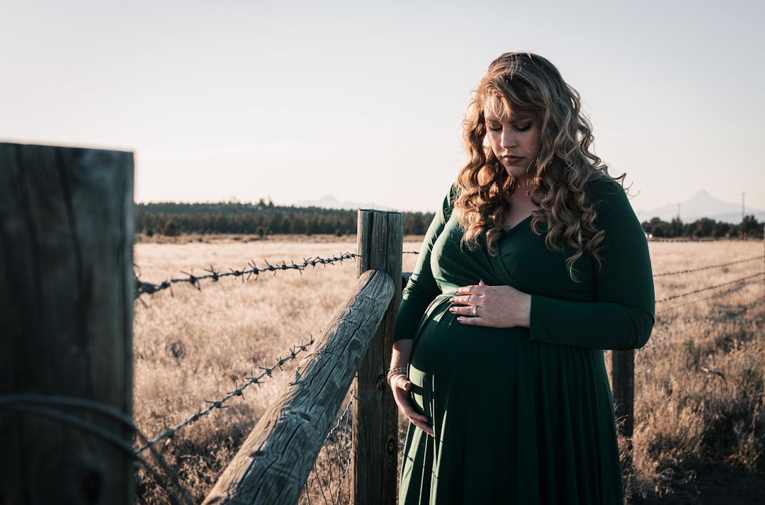 woman in black dress standing beside brown wooden fence during daytime