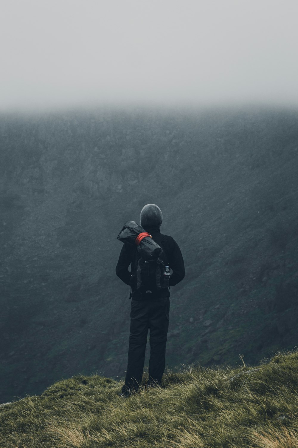 man in black jacket and black pants standing on cliff