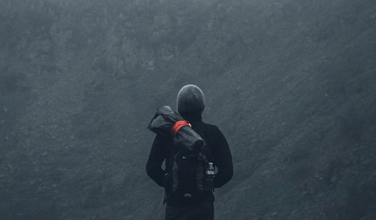 man in black jacket and black pants standing on cliff