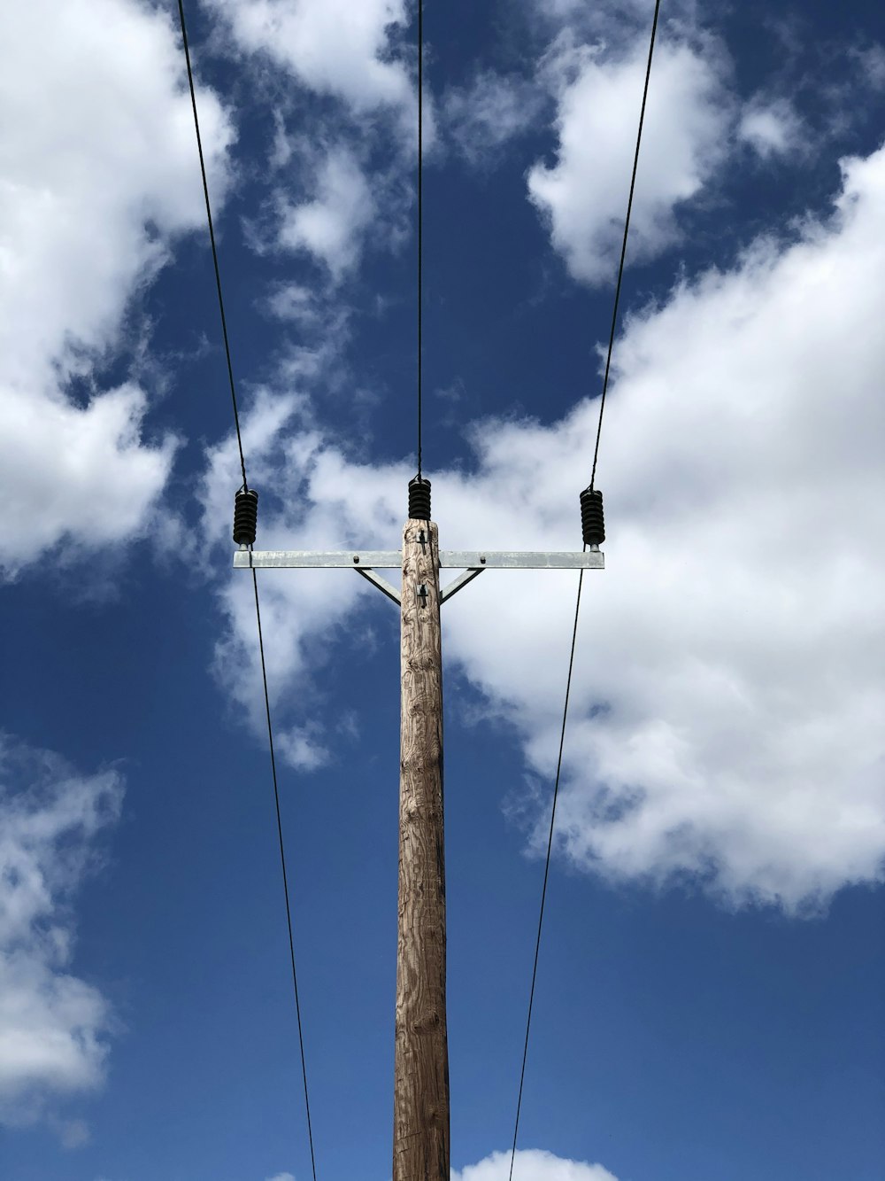 brown wooden electric post under blue sky