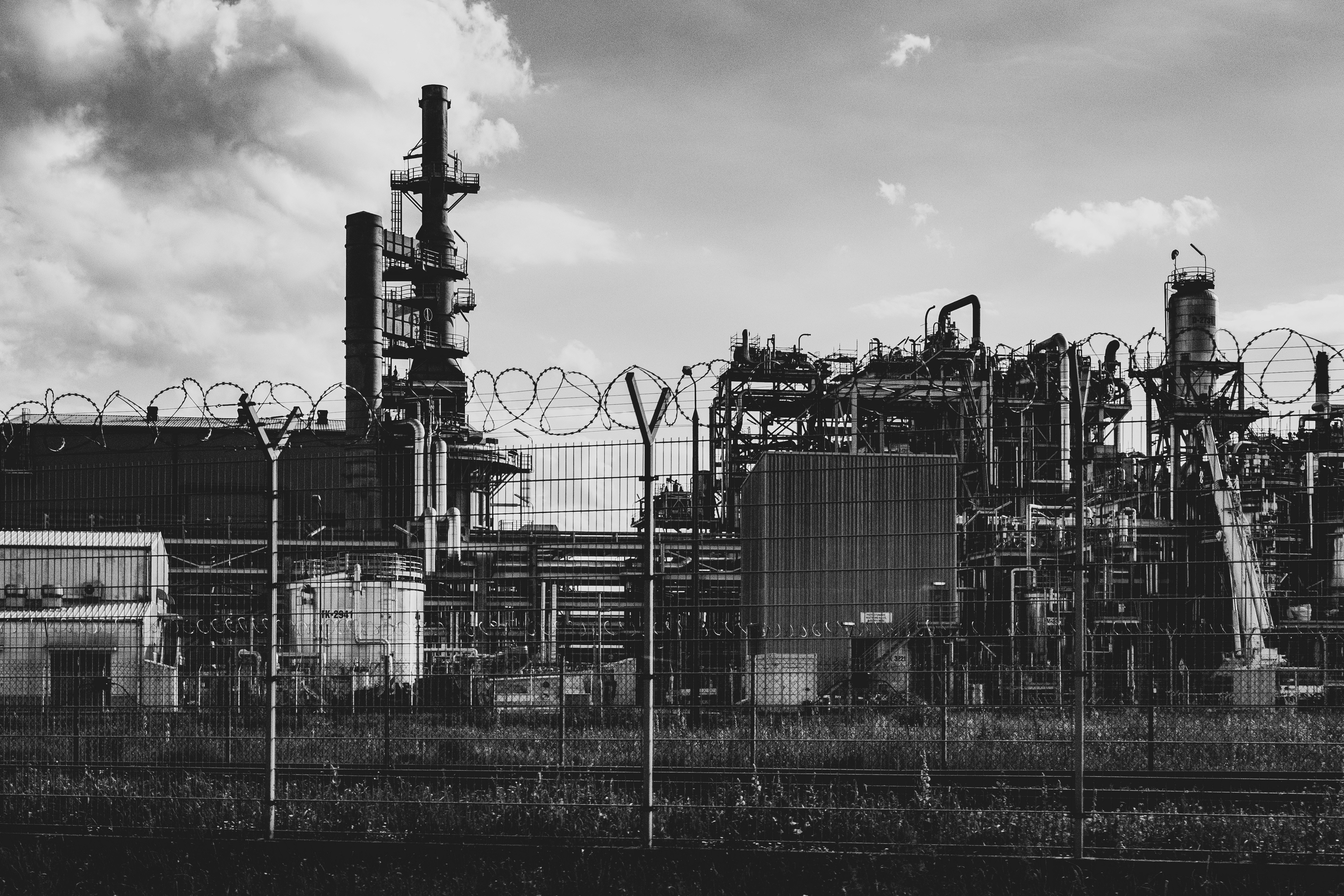 grayscale photo of factory under cloudy sky