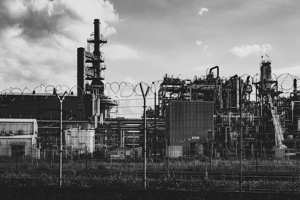 grayscale photo of factory under cloudy sky