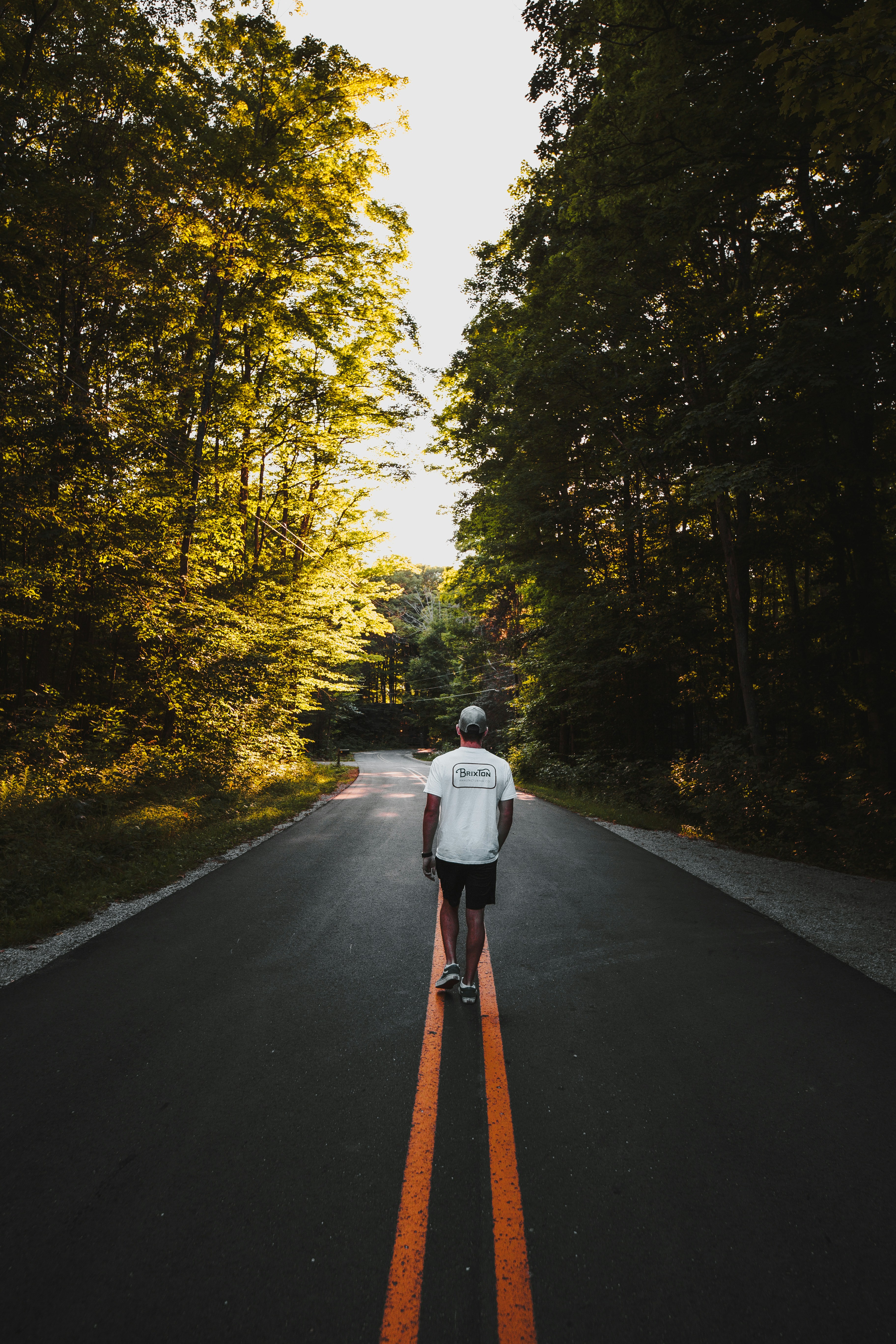 man in white jacket and black pants sitting on road during daytime
