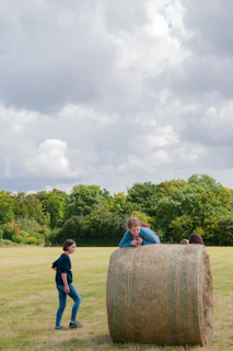 Children playing around bales of hay while families chat in the background at a farm gathering
