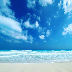 A serene beach scene with a clear blue sky and gentle waves, inviting relaxation.
