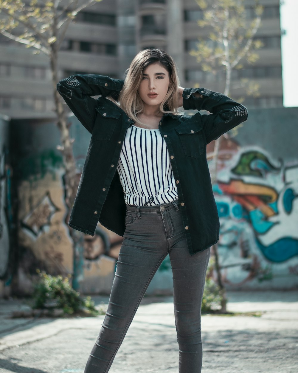 woman in black jacket standing near wall with graffiti during daytime