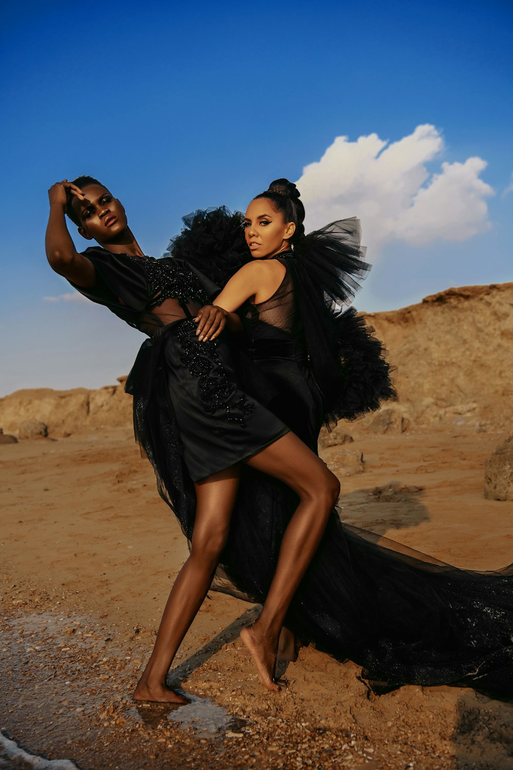 femme en robe noire debout sur le sable brun pendant la journée